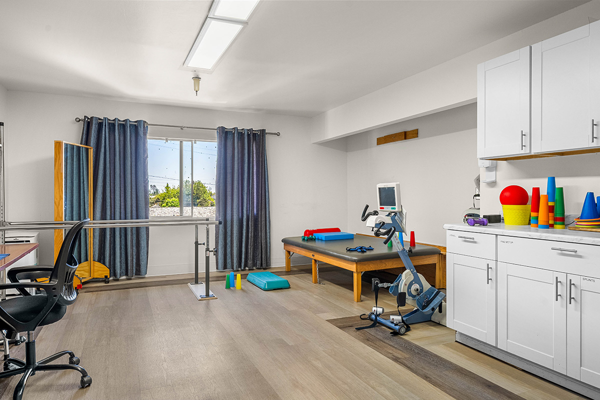 Bright therapy room with exercise equipment and colorful objects.