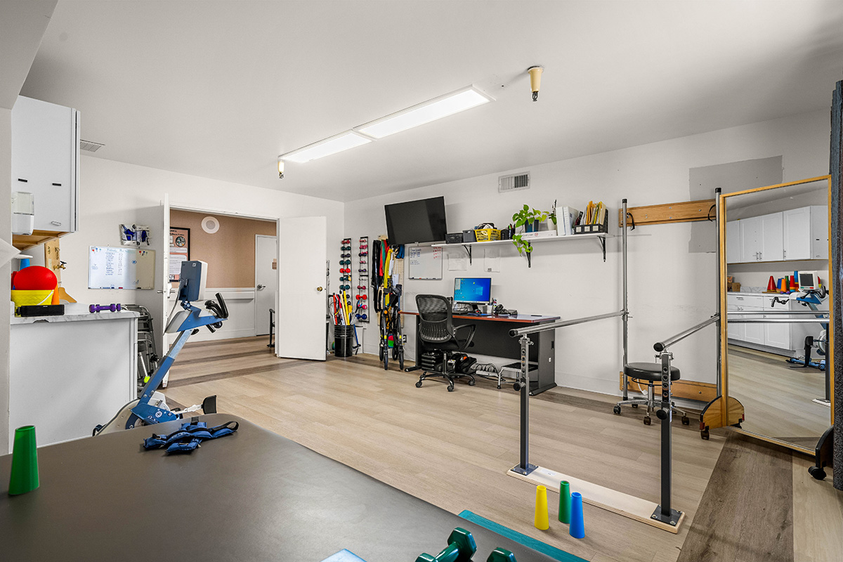 Workout space with equipment, desk, and mirrored area.
