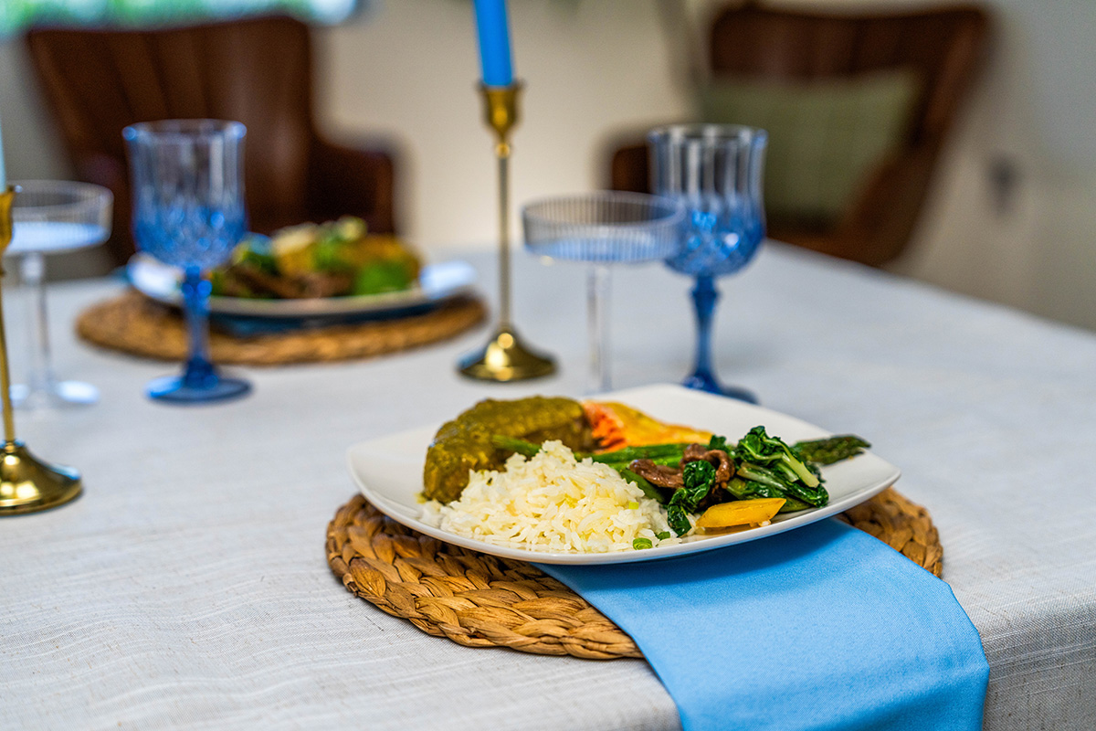 Plate of rice, vegetables, and dinnerware on a table.