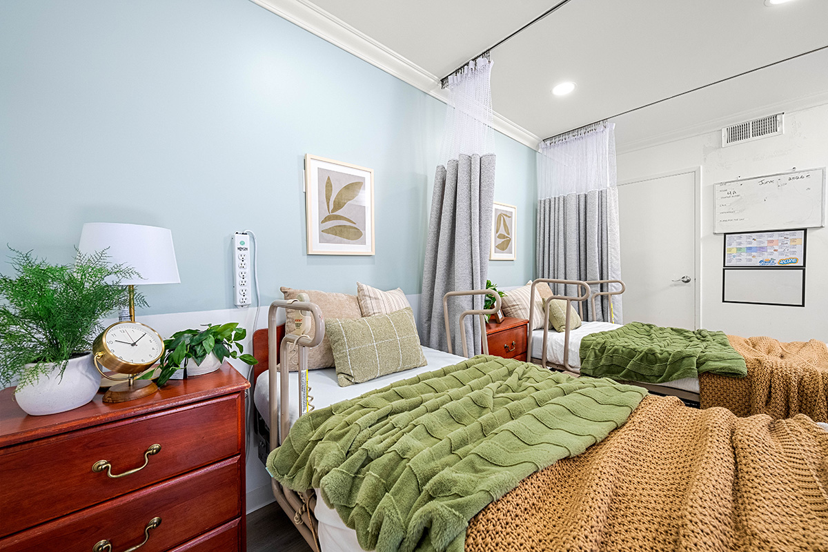 Cozy, shared bedroom with decorative blankets and plants.