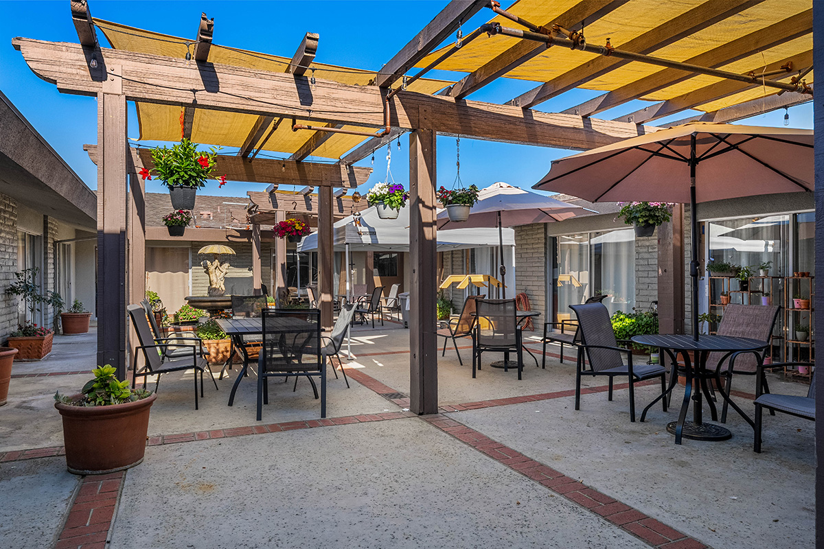 Outdoor seating area with shade, plants, and colorful umbrellas.