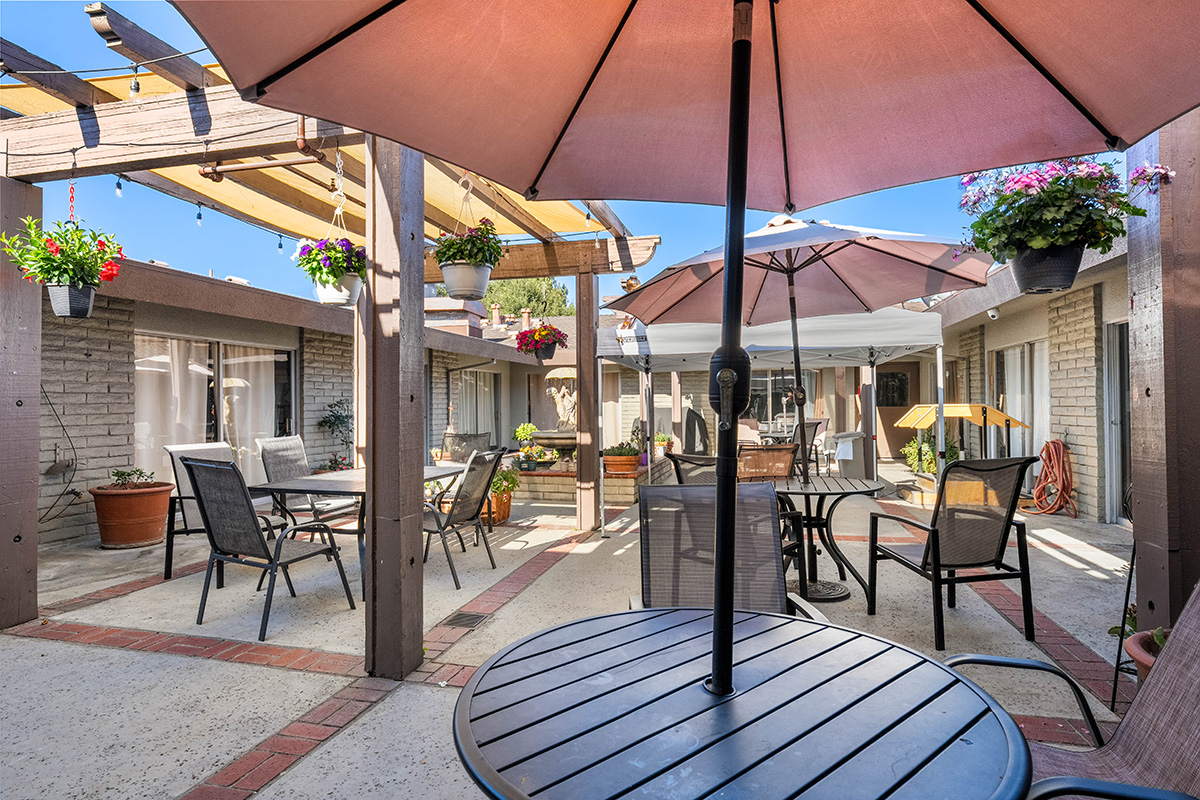 Outdoor seating area with umbrellas and plants.